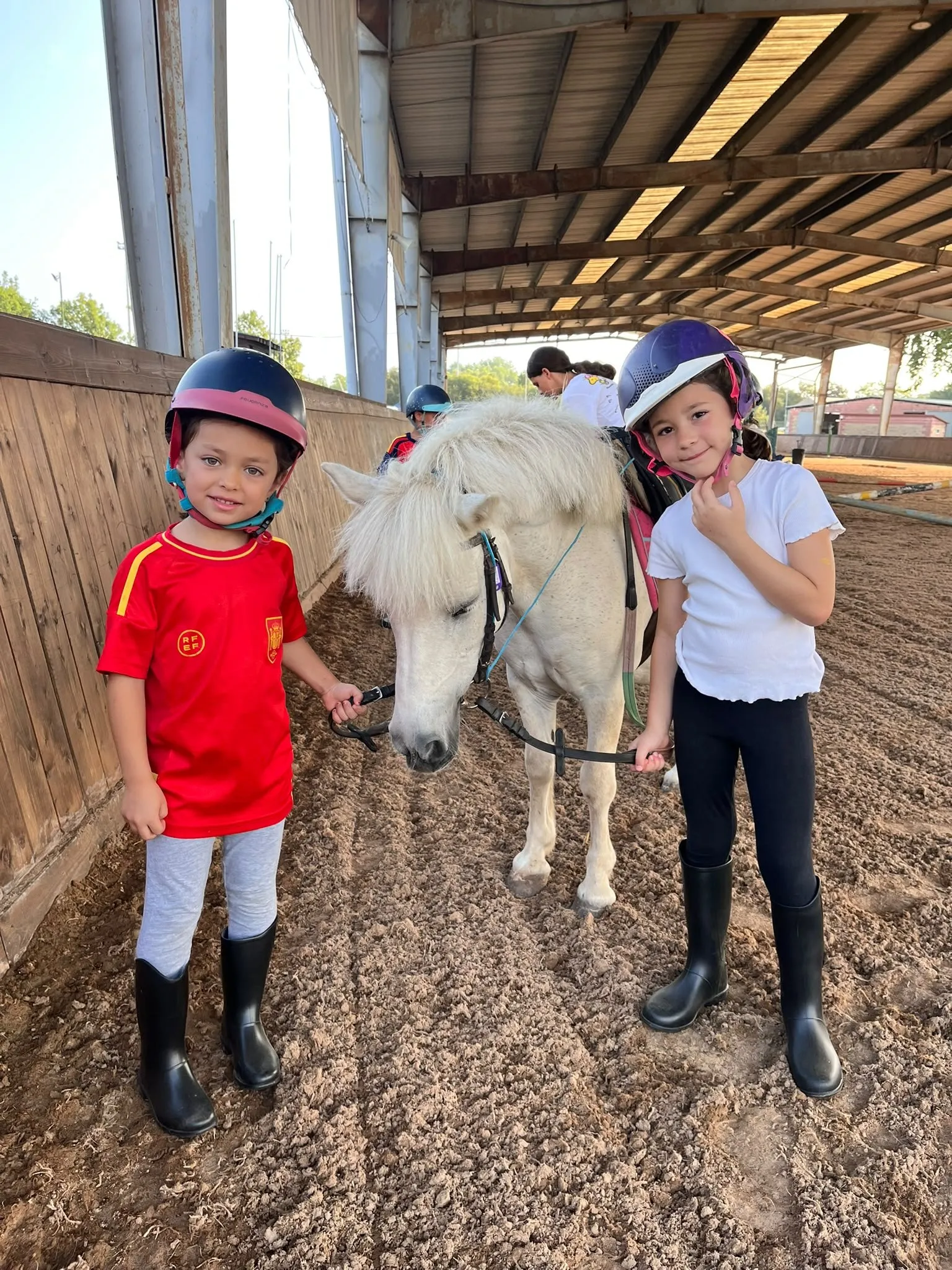 Niños con un poni blanco en la pista cubierta del CHAS