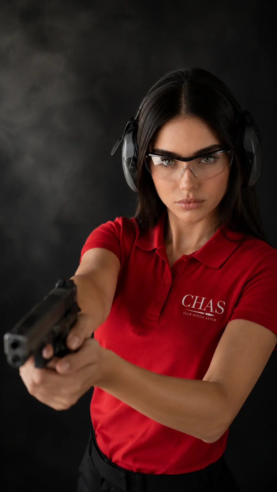 Tiradora con cascos de protección y gafas de seguridad apuntando con una pistola